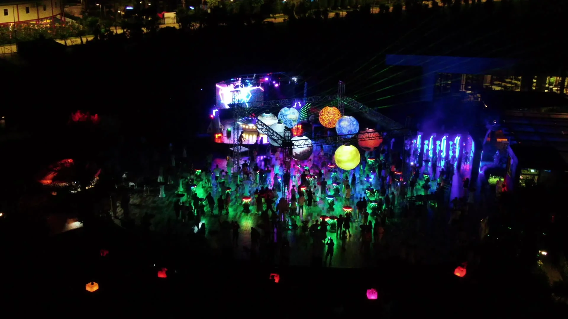 Vista aérea de un evento nocturno EEC con público, esferas iluminadas y láseres de colores